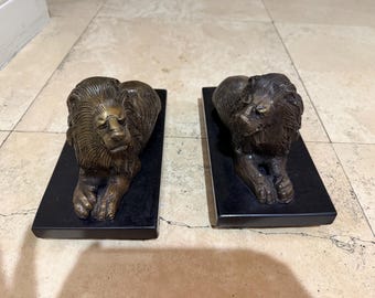 Sculptures de lions de la Bombay Company, paire de lions couchés en bronze massif sur socles noirs, décoration traditionnelle pour cheminée de bibliothèque.