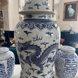 May include: A large, blue and white ceramic ginger jar with a dragon design. The jar has a lid with a small lion statue on top. Two smaller matching jars are also visible.