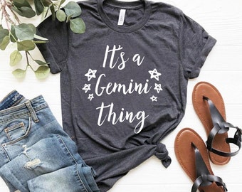 May include: A dark gray t-shirt with the text "It's a Gemini thing" in white lettering. The text is surrounded by small white stars.