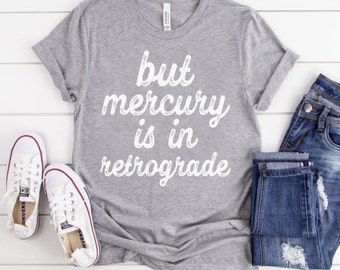 Puede incluir: Camiseta gris con el texto "but mercury is in retrograde" en letras blancas.