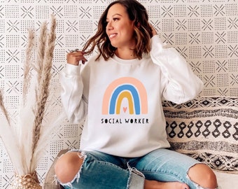 May include: White sweatshirt with a rainbow graphic and the text "SOCIAL WORKER".