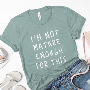 Puede incluir: Una camiseta azul claro con el texto "I'm not mature enough for this" impreso en blanco.