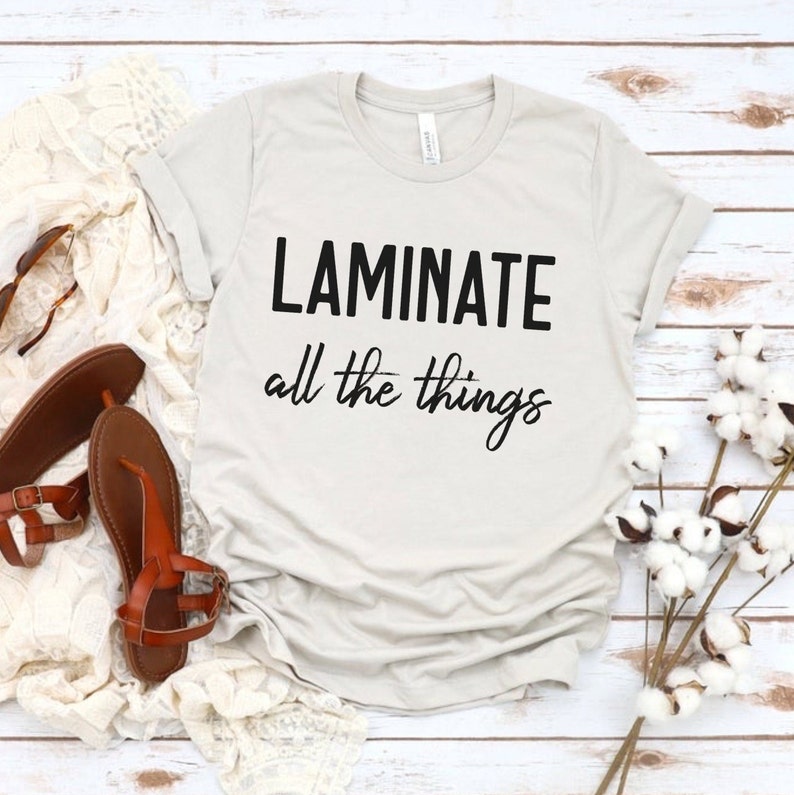 Puede incluir: Una camiseta gris claro con el texto "LAMINATE all the things" en negro.