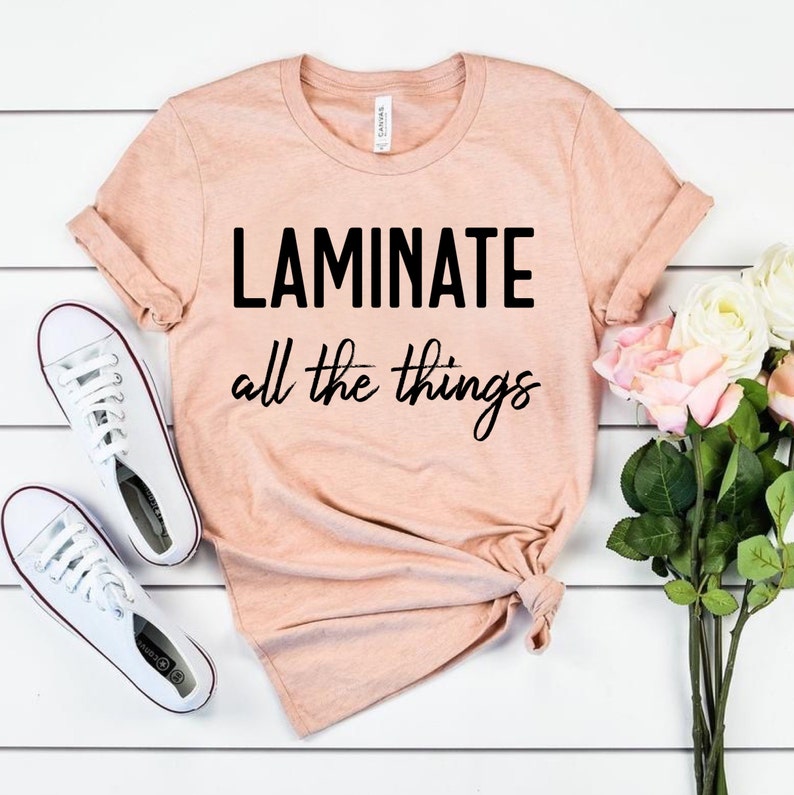Puede incluir: Una camiseta rosa claro con el texto "LAMINATE all the things" en negro.