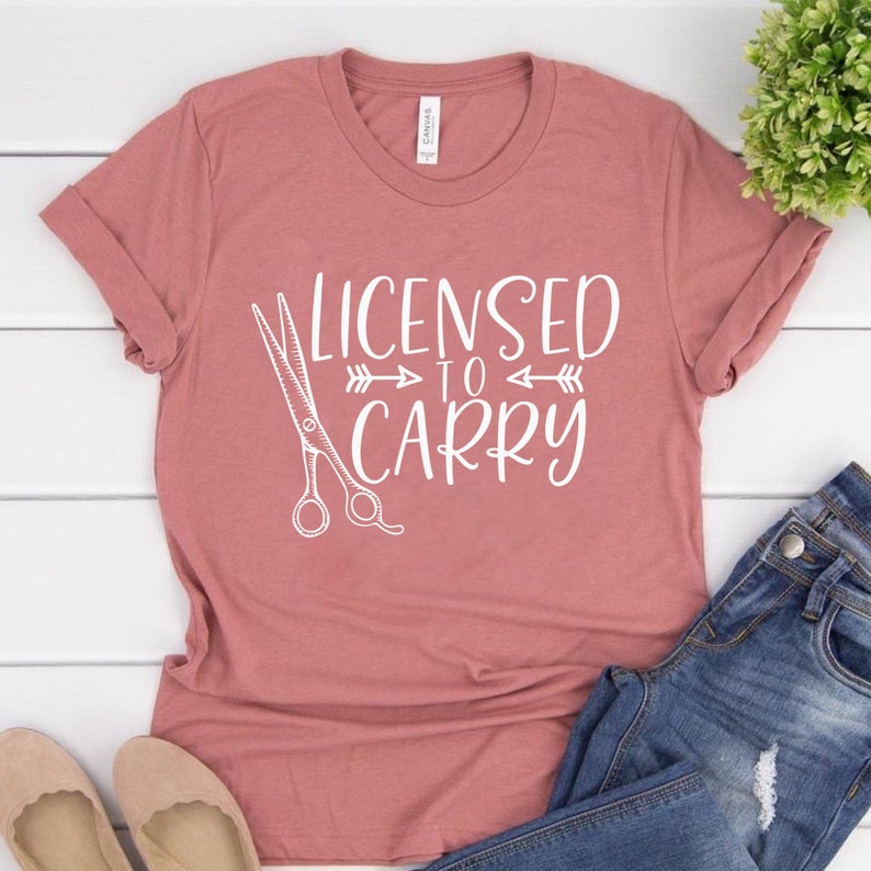May include: A pink t-shirt with the text "Licensed to Carry" and a pair of scissors graphic.