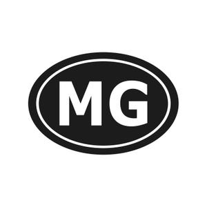 Op de afbeelding: Een zwart-witte ovale sticker met de witte letters "MG". De letters zijn gecentreerd in de zwarte ovaal, die is omlijnd met een dunne witte rand.