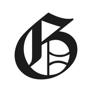 May include: A black, stylized letter "G" in a gothic font. The letter has a bold, ornate design with sharp angles and curves, set against a white background. The design is a classic example of typography.