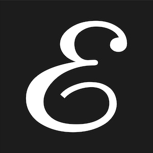 May include: A white, stylized letter "E" against a solid black background. The letter has a classic, elegant serif font with a rounded top and a flowing, curved design. The contrast between the white letter and the black backdrop creates a bold visual.