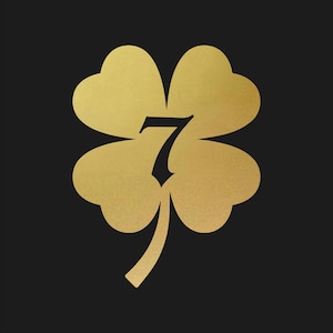May include: A gold-colored four-leaf clover with the number 7 in the center, set against a black background. The clover has a textured, metallic appearance, and the number is in a stylized font. The overall design is simple and elegant.
