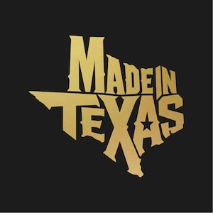 Puede incluir: Texto dorado sobre fondo negro que dice "MADE IN TEXAS" en una fuente estilizada con la forma del estado de Texas. Una estrella está incorporada en el diseño.