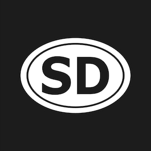 Könnte beinhalten: Ein weißer ovaler Aufkleber mit schwarzem Rand und den Buchstaben "SD" in fetter, schwarzer Schrift. Der Aufkleber ist vor einem schwarzen Hintergrund platziert.