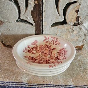May include: Three white ceramic bowls with a pink floral pattern. The bowls are stacked on top of each other.