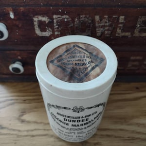 May include: A white ceramic jar with a black and white label that reads "James Keiller & Son Ltd. Dundee Orange Marmalade Est. 1797".