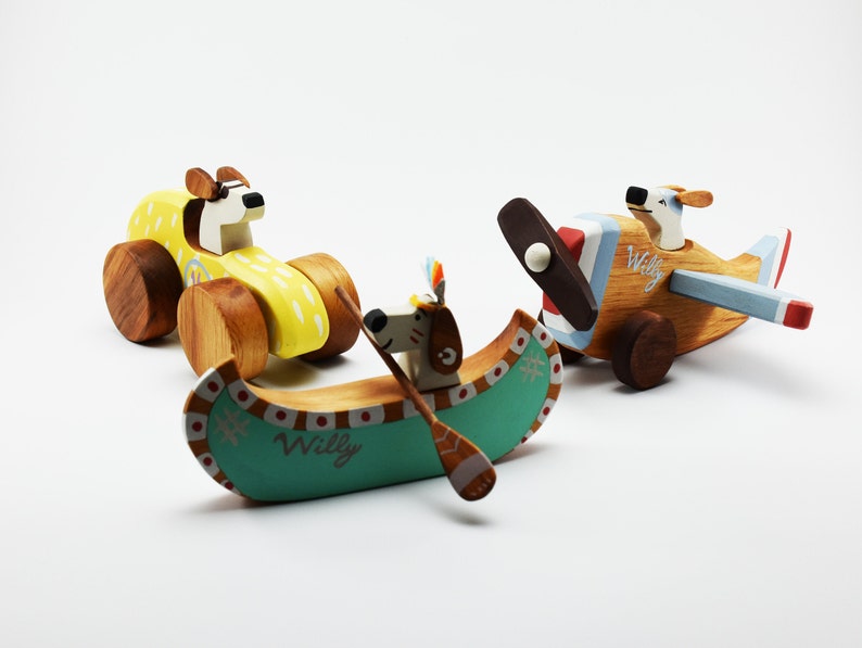 May include: Three wooden toy vehicles featuring a dog character. A yellow car, a blue and red airplane, and a green canoe with a dog paddling.