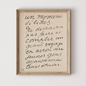 May include: A framed print with handwritten script in black ink on a beige background. The text includes the phrase "un moment d'libres" and other French text. The frame is a light wood color, and the number "54" is in the lower left corner.
