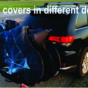 May include: A black SUV with a bike cover on the back. The cover has a blue and black geometric design.