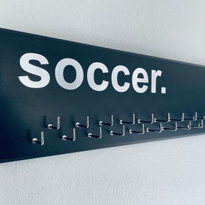 Soccer Medal Holder, black or gray with carbon silver "soccer." vinyl, medal hanger with 11 or 21 hooks.
