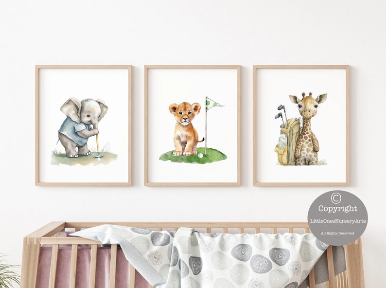 Puede incluir: Tres ilustraciones de acuarela de animales jugando al golf. Un elefante balancea un palo de golf, un le&oacute;n se para en un green con una pelota de golf y una bandera, y una jirafa se para junto a una bolsa de golf.
