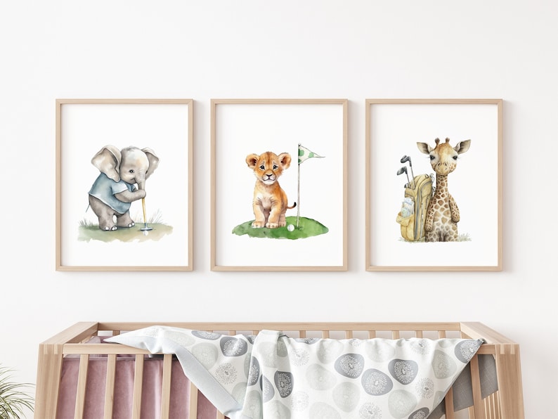 Puede incluir: Tres acuarelas enmarcadas de animales jugando al golf. La primera pintura presenta un elefante sosteniendo un palo de golf, la segunda pintura presenta un le&oacute;n con una bandera de golf y la tercera pintura presenta una jirafa con una bolsa de golf.