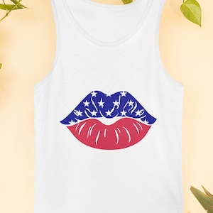 May include: White vest top with a graphic of lips. The upper lip is blue with white stars, and the lower lip is red. The vest top is hanging on a clothesline with green vines.
