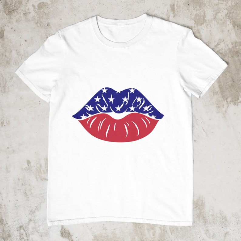 May include: White t-shirt with a graphic of lips. The upper lip is blue with white stars, and the lower lip is red. The design is centered on the shirt, creating a patriotic theme.