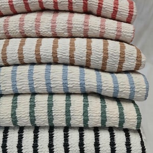 May include: A white ceramic mug with a black handle and the text "But First, Coffee" in a handwritten style. The mug is on a white surface. The mug is approximately 4 inches tall.