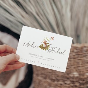 May include: A white wedding invitation card with a watercolor illustration of a squirrel on a branch with red berries. The text on the card reads "Andrea & Michael" and "December 22, 2023 |  Cole, FL |  Wedding Invitation".