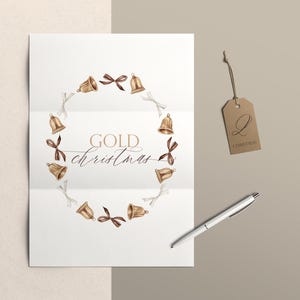 May include: A white folded paper featuring a watercolor wreath of gold bells and brown and white ribbons. The text reads GOLD christmas in the center. A brown kraft paper tag with the letter Q and the word CHRISTMAS hangs nearby with a pen.
