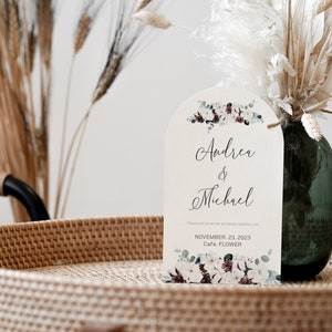 May include: A white wedding invitation with a floral design and the names Andrea & Michael. The invitation states the date is November 23, 2023 and the location is Cafe Flower.