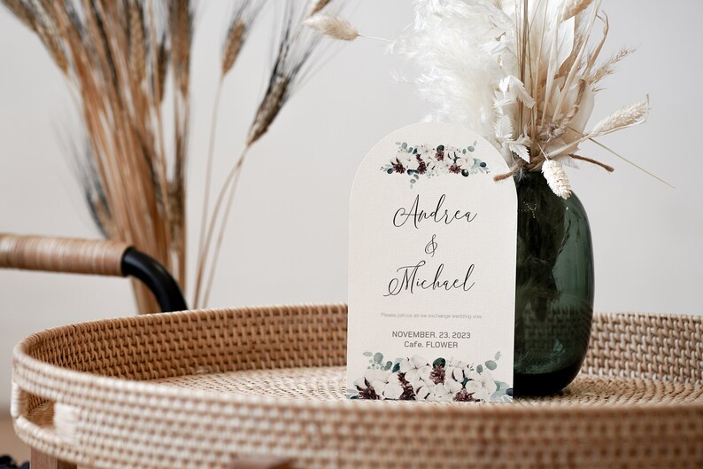 May include: A white wedding invitation with a floral design and the names Andrea & Michael. The invitation states the date is November 23, 2023 and the location is Cafe Flower.