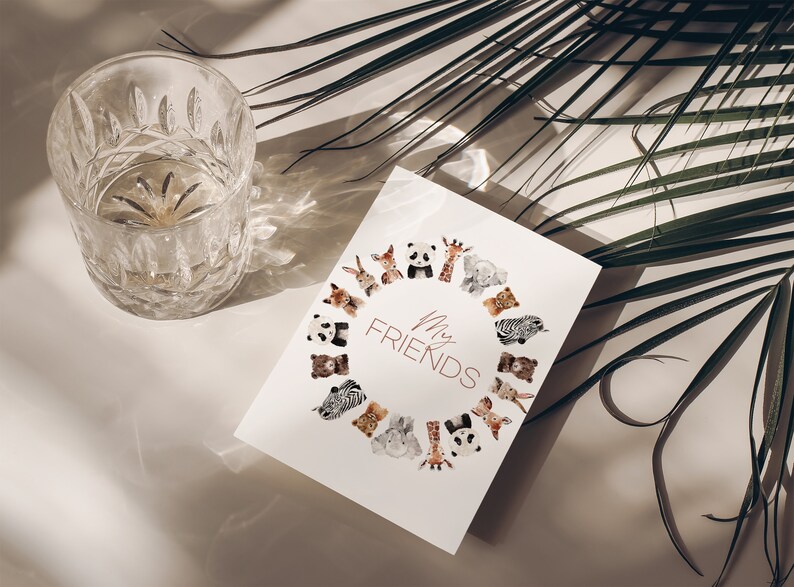 May include: A white card featuring the text "My Friends" encircled by watercolour illustrations of animals such as pandas, giraffes, and zebras. A clear, patterned glass is positioned to the left. Palm leaves are in the background.