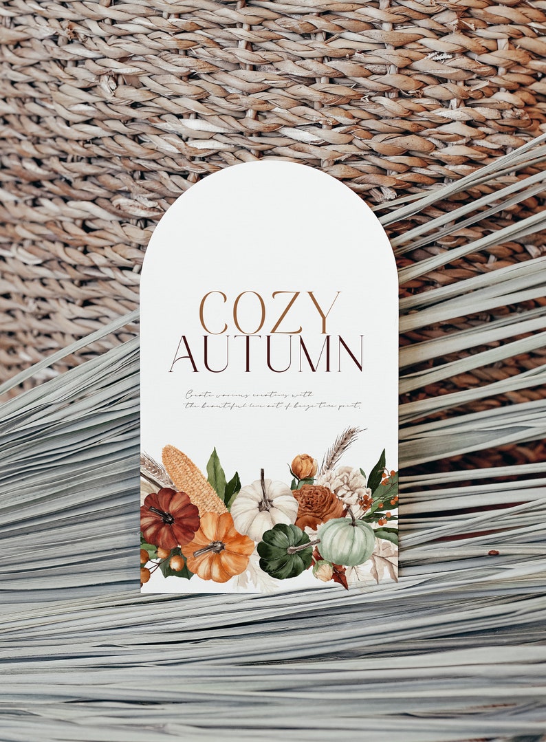 Peut inclure: Une carte blanche avec le texte "COZY AUTUMN" en lettres brunes. La carte pr&eacute;sente une illustration aquarelle de citrouilles, de ma&iuml;s et de fleurs.