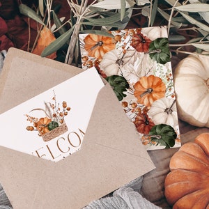 Peut inclure: Une enveloppe en papier kraft avec une carte blanche &agrave; l'int&eacute;rieur. La carte pr&eacute;sente une illustration aquarelle d'un panier rempli de citrouilles, de courges et de feuillage d'automne. Le texte "Bienvenue" est imprim&eacute; sur la carte. L'enveloppe est entour&eacute;e de feuilles d'automne, de citrouilles et de branches d'olivier.
