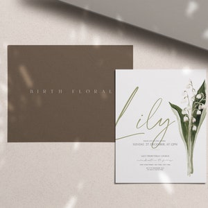 Puede incluir: Una tarjeta blanca con el nombre "Lily" escrito en cursiva. La tarjeta presenta una ilustraci&oacute;n de acuarela de un ramo de flores blancas de lirio de los valles con hojas verdes. El texto "Save the Date" est&aacute; impreso en una fuente m&aacute;s peque&ntilde;a debajo del nombre. La tarjeta est&aacute; sobre un fondo marr&oacute;n claro.