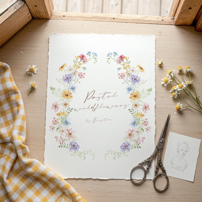 May include: A watercolor print featuring a floral wreath of pastel wildflowers. The artwork includes text that reads "Pastel wildflowers" and "by: Bridgetine". A pair of decorative scissors and a sketch are next to the print.