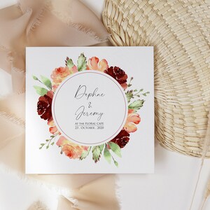 May include: A wedding invitation with a watercolor floral wreath in shades of red, orange, and green. The invitation reads "Daphne & Jeremy" and "At the Floral Cafe, 23 October, 2020".