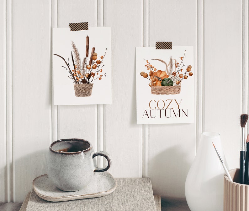 Peut inclure: Deux impressions d'art imprimables sur le th&egrave;me de l'automne. Les impressions pr&eacute;sentent des illustrations &agrave; l'aquarelle de fleurs s&eacute;ch&eacute;es et de courges dans des paniers. Le texte sur l'une des impressions est "Cozy Autumn".