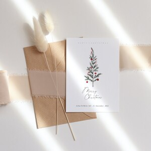 May include: A white card with a simple illustration of a Christmas tree with red ornaments and the text "Merry Christmas" and "At The Floral Cafe, 22 December 2022".