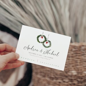 May include: A white wedding invitation with a simple design featuring two green wreaths with red berries. The text reads "Andrea & Michael" and "December 23, 2023 - Cafe, FLOWER. Please join us as we exchange wedding vows."