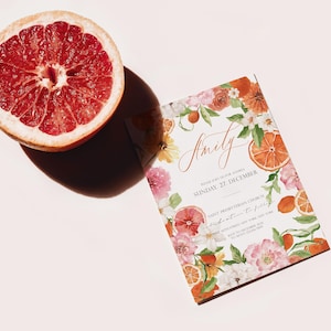 May include: A white wedding invitation with a floral design featuring oranges, lemons, and pink flowers. The text on the invitation reads "Emily" and "Sunday, 27 December".