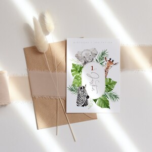 May include: A birthday invitation with watercolour illustrations of a baby elephant, giraffe, and zebra, surrounded by tropical leaves. The invitation includes the text "1st Justin" in an oval frame, with the words "BIRTHDAY | INVITATION" at the top.