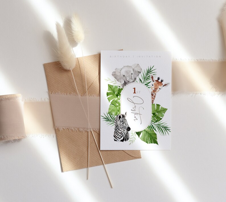 May include: A birthday invitation with watercolour illustrations of a baby elephant, giraffe, and zebra, surrounded by tropical leaves. The invitation includes the text "1st Justin" in an oval frame, with the words "BIRTHDAY | INVITATION" at the top.
