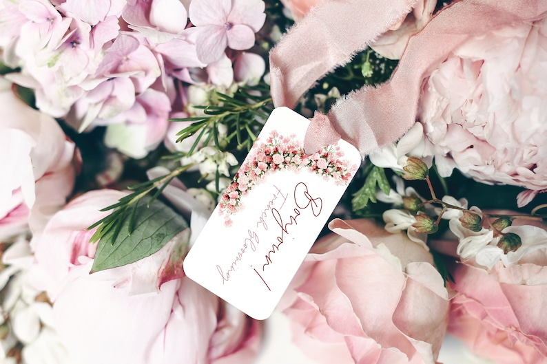 May include: A white gift tag with a pink floral border and the text "Happy Flowers!" in red cursive. The tag is attached to a bouquet of pink flowers.