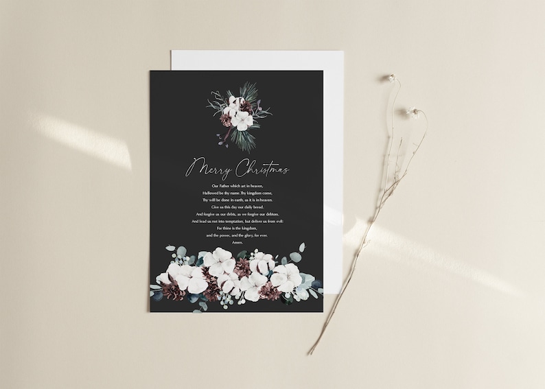 May include: A black Christmas card with a white floral design and a silver inscription that reads "Merry Christmas". The inscription continues with a passage from the Lord's Prayer: "Our Father which art in heaven, Hallowed be thy name. Thy kingdom come. Thy will be done in earth, as it is in heaven. Give us this day our daily bread. And forgive us our debts, as we forgive our debtors. And lead us not into temptation, but deliver us from evil. For thine is the kingdom, and the power, and the glory, for ever and ever. Amen."