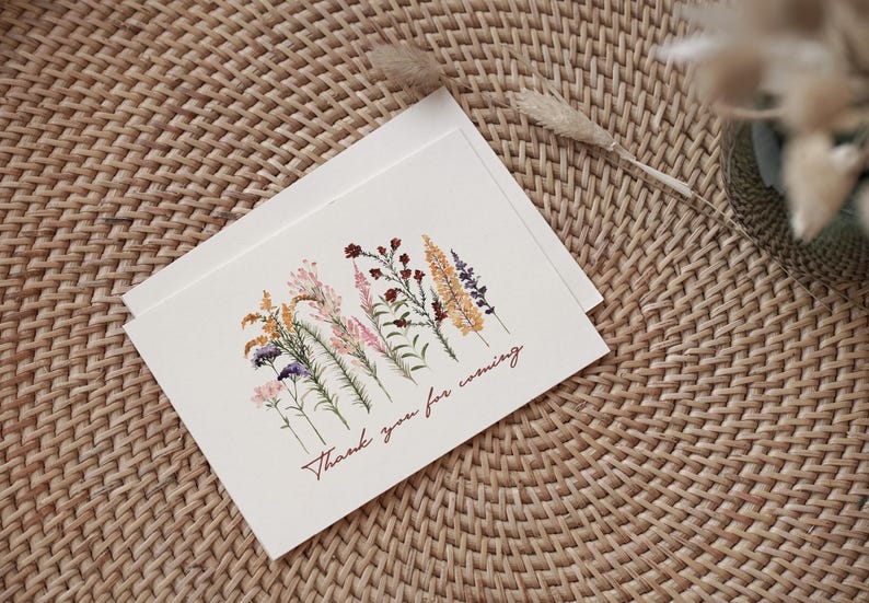 May include: A white card with a floral design and the text "Thank you for coming". The flowers are pressed and dried, and they are in shades of pink, yellow, and purple.