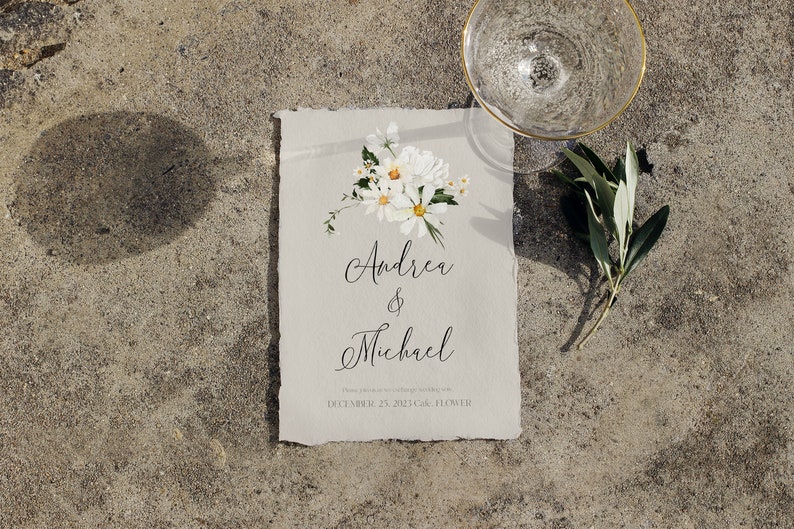 May include: A wedding invitation with a white background and a floral design in the top right corner. The text reads "Andrea & Michael" and "December 27, 2021, Cal. Flower."