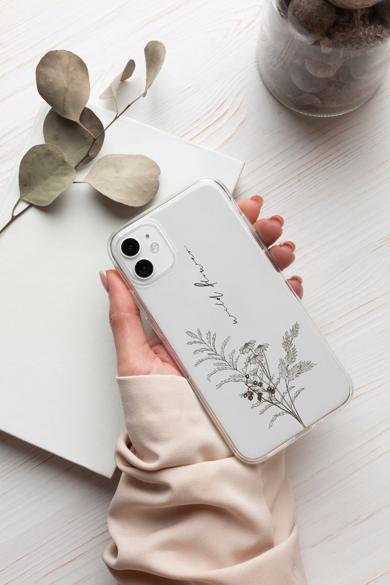 May include: A white phone case with a floral design and the text "wild flower" printed on it.