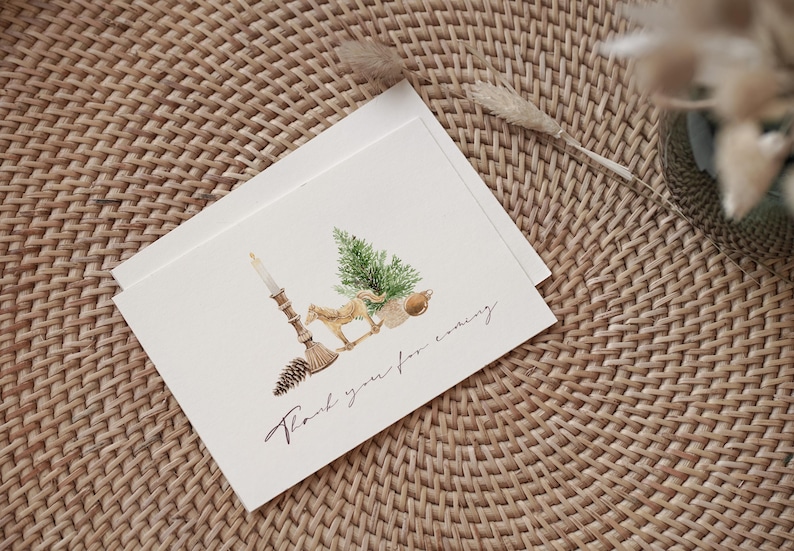 May include: A white folded greeting card featuring a watercolor illustration of a lit candle, a pinecone, a small horse figurine, a green pine tree, and a round ornament. The text "Thank you for coming" is printed in a black cursive script below.