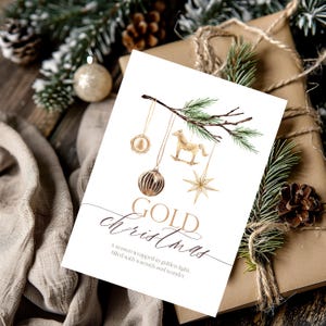 May include: A white greeting card featuring a watercolor illustration of a pine branch with hanging gold ornaments including a rocking horse, a star, and a round bauble. The text reads GOLD christmas, A season wrapped in golden light, filled with warmth and wonder.