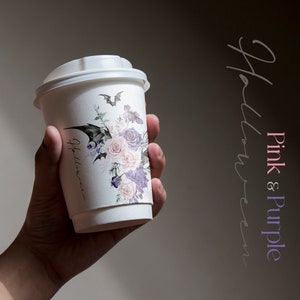 May include: A white paper coffee cup with a pink and purple floral design and a bat graphic. The text "Halloween" is written on the cup.
